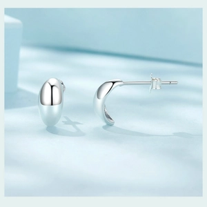 Macro shot of silver drop stud earrings showing minimalist geometric metallic finish