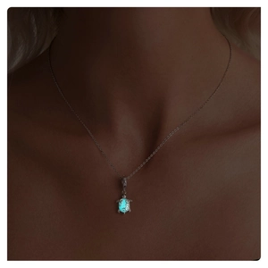 Luminous sea turtle pendant glowing in blue light against dark background close-up
