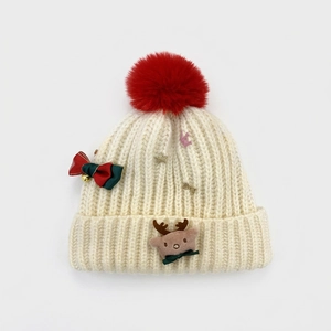 Detail of knit beanie with reindeer applique, sequins, and red faux fur pom-pom topper