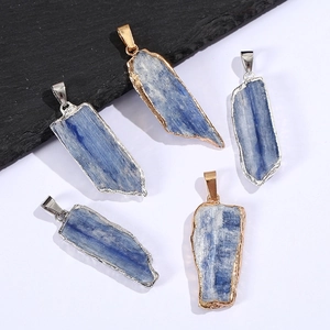 Set of 5 raw blue kyanite pendants with gold and silver plated edges on rock background