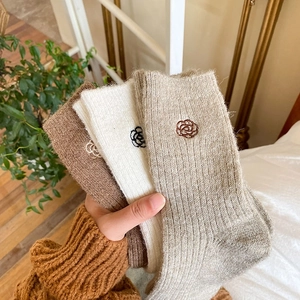Detail of winter wool socks featuring delicate camellia embroidery and thick knit texture
