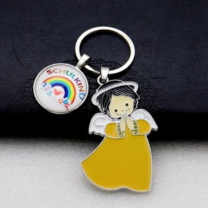 Detail of metal keychain with rainbow and angel pendants on black leather background