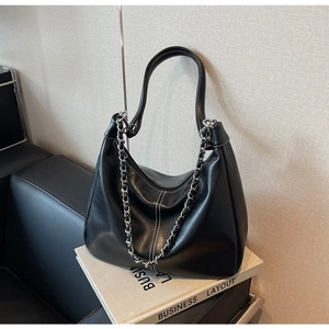 Detail of black hobo bag with white contrast stitching and decorative silver chain strap