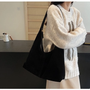 Model wearing a black suede hobo bag for women with high capacity and minimalist design
