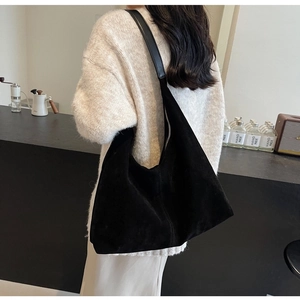 Detail of a black suede large tote bag styled as an elegant underarm shoulder bag