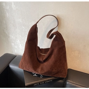 Detailed texture of brown suede hobo bag placed on a black art book with soft lighting