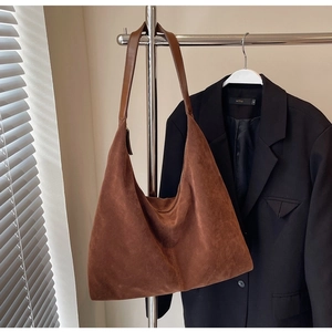 Detail of caramel brown suede hobo bag featuring decorative stitching and leather strap