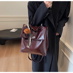 Side view of dark red glossy backpack with silver buckle and brown plush puppy charm