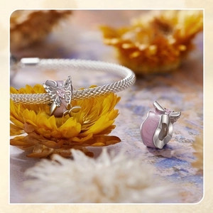 Detailed macro shot of silver butterfly charm with pink heart zircon and enamel inlay
