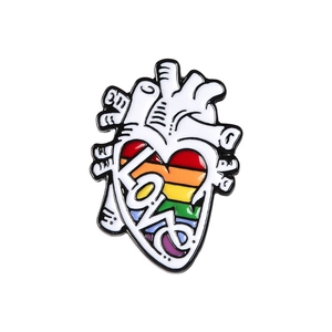 Detail of anatomical heart enamel pin with rainbow colors and handwritten LOVE text