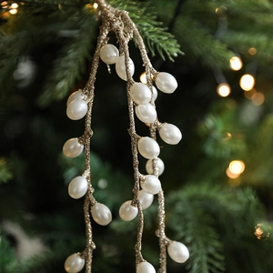 Christmas faux pearl berry branch with white beads and gold glitter on a green tree