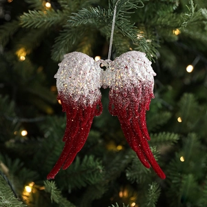 Christmas angel wing ornament with silver sequins and red flocking on a tree branch