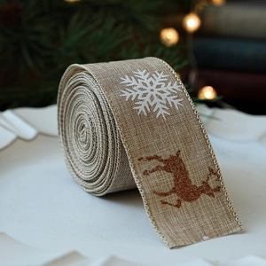 Christmas burlap ribbon roll with white snowflakes and red reindeer on wooden plate
