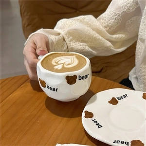 Hand-painted ceramic coffee cup with bear pattern on a cozy wooden table background