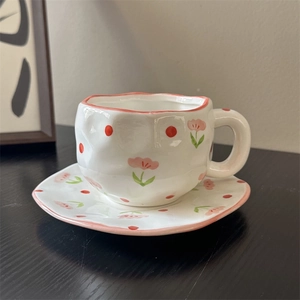 Macro view of handmade ceramic coffee cup with hand-painted floral pattern and wavy edges