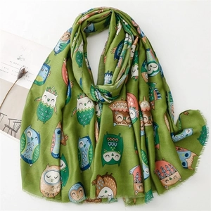 Close-up of green cotton-linen scarf featuring colorful owl patterns and frayed tassels