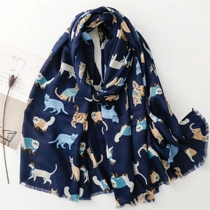 Dark blue cotton scarf with cartoon cat patterns and tassels on a flat lay background