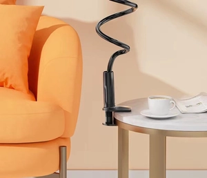 Adjustable black long arm tablet holder clamped to a marble table in a cozy home setting
