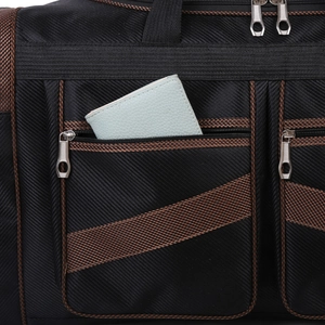 Close-up of black nylon travel bag showing twill texture and brown strap details