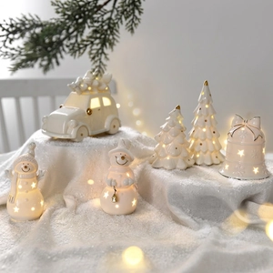 Luminous white ceramic Christmas ornaments with LED stars and gold accents on snow