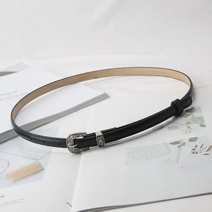 Detail of vintage silver floral engraved buckle on a slim black leather waist belt