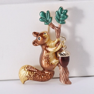 Detail of an enamel squirrel brooch with acorns and green leaves on a white box