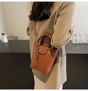 Chic brown leather bucket bag with woven detail worn by a model in a cafe setting