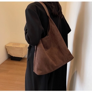 Rear view of a model wearing a brown faux suede shoulder bag with a minimalist design