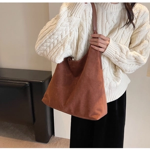 Close-up of brown suede tote bag styled with a cozy white sweater for a casual commute look