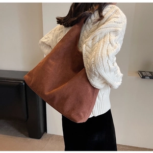 Brown faux suede tote bag shown on a model wearing a white knitted sweater