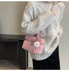 Detailed close-up of pink faux shearling crossbody bag with fluffy texture and metal zipper