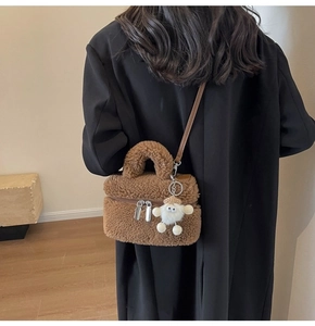 Detailed back view of a brown plush crossbody bag with leather strap and cute charm