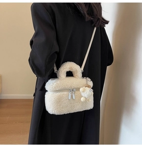 White faux fur crossbody bag with matching plush charm worn by model in casual style