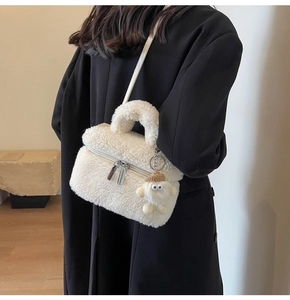 Close-up of white faux shearling crossbody bag with cute plush doll charm accessory