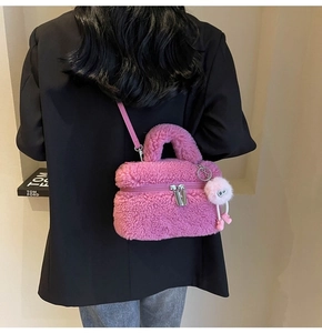 Detail of pink faux shearling crossbody bag with fuzzy pom-pom and silver zipper