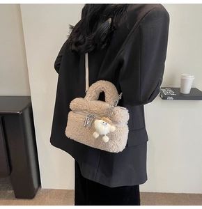 Close-up of beige fleece crossbody bag featuring a cute plush doll with a straw hat