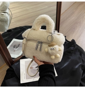 Detail of off-white plush bucket bag with silver zipper and cute teddy bear pendant