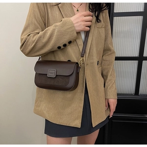 Detail of dark brown crossbody bag in smooth and matte leather on a blazer outfit
