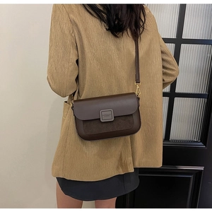Dark brown faux leather crossbody bag with gold hardware shown on a person's shoulder