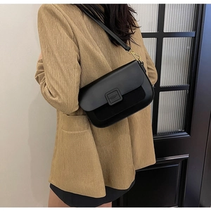 Close-up of black crossbody bag with mixed leather textures and gold hardware buckle