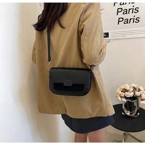 Chic black leather crossbody bag for women with gold clasp worn by model in a studio