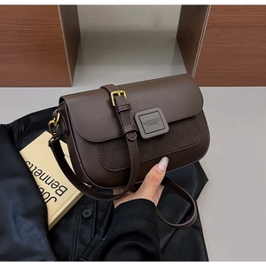 Detailed shot of brown leather shoulder bag with gold hardware and flap closure