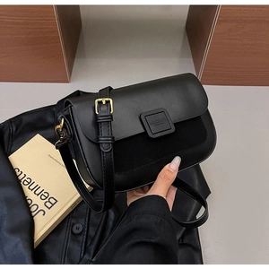 Detail of black crossbody bag featuring smooth leather texture and metallic buckle