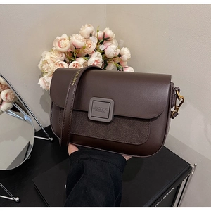 Detailed view of dark brown crossbody bag with matte suede texture and metal logo
