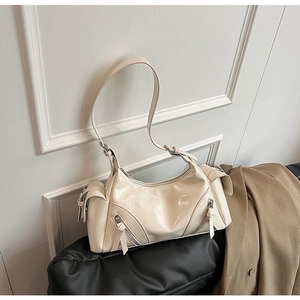 Close-up of beige dumpling bag with zipper pockets and tassel details in biker style