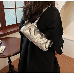Detail of silver metallic Y2K shoulder bag with pleated texture and buckle on model