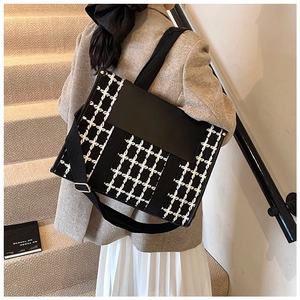 Detail shot of black and white houndstooth tote bag with black PU leather flap and wide strap
