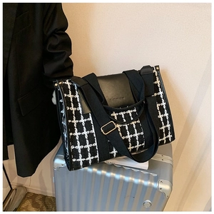 Detail of black and white checkered tweed tote bag placed on a silver suitcase