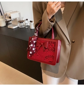 Detail of red bridal handbag with floral embroidery and heart pattern scarf wrap