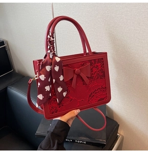 Detailed macro view of the red lace embroidery and 3D bow on this red bridal handbag